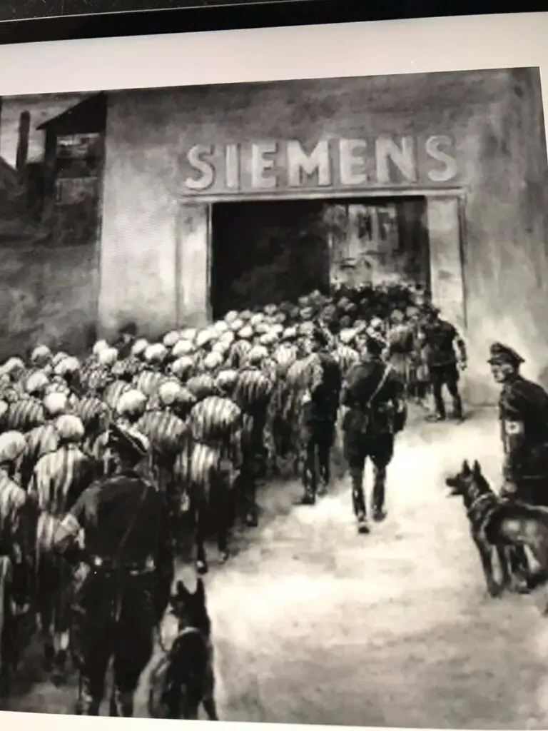 Slave laborers going inside a Siemens building while Nazi guards direct them.