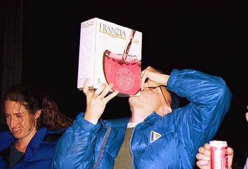 A man in a bar guzzling a box of Franzia wine, which is the cheapest drink and definitely the best way to get super drunk.