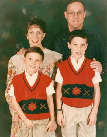 A family picture with two siblings where the other one scratches his penis.