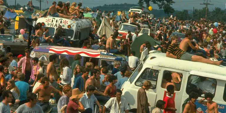 Crowds gather during the first Woodstock Festival. Some of them are on the roofs of their vehicles.