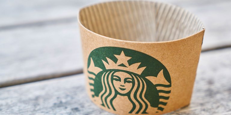 A paper coffee of Starbucks showing its green mermaid logo.