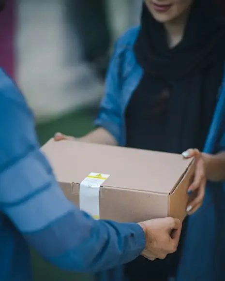 A man handing out a box of parcel to a woman.