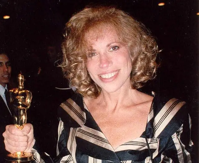 Singer Carly Simon holding a trophy.