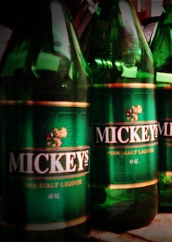 Green bottles of Mickey's 40 Oz Malt Liquor displayed on a supermarket shelf.