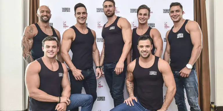 Men in black sleeveless shirts posing for a group picture.