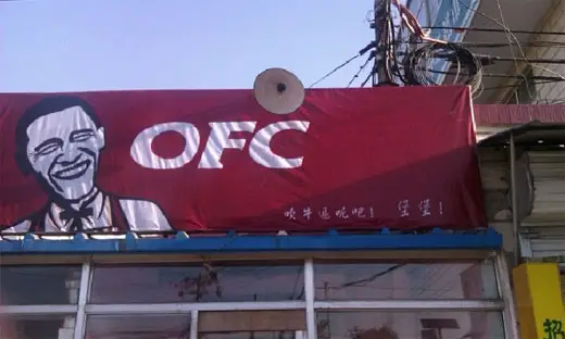 A restaurant bearing the initials OFC in white font written in red background with the face of a smiling Barrack Obama. Clearly a ripoff of KFC restaurant.