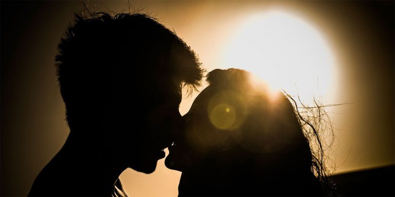A silhouette of a man and woman kissing.