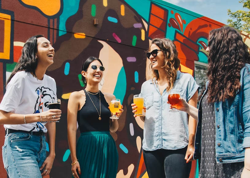 Four women friends gathered together with drinks in their hands to chat and have fun.