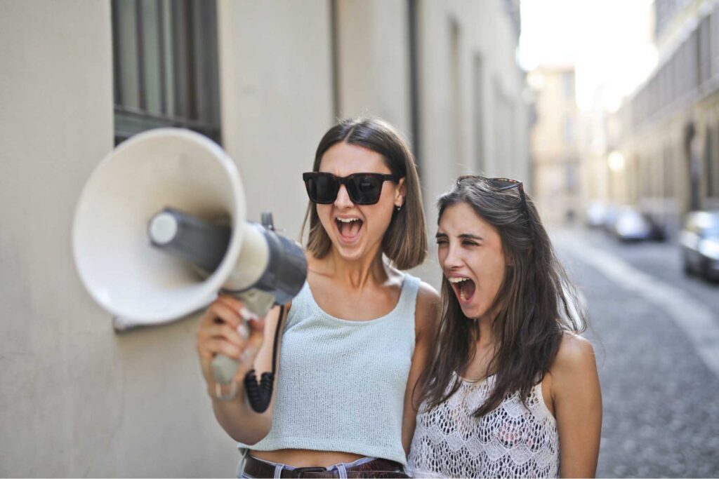 Two women having fun with a megaphone.