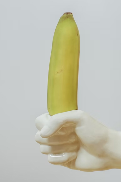 A white plastic hand holding a banana.