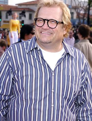 Drew Carey with eyeglasses and a crowd behind him.