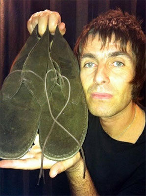 Liam Gallagher holding up a pair of shoes.