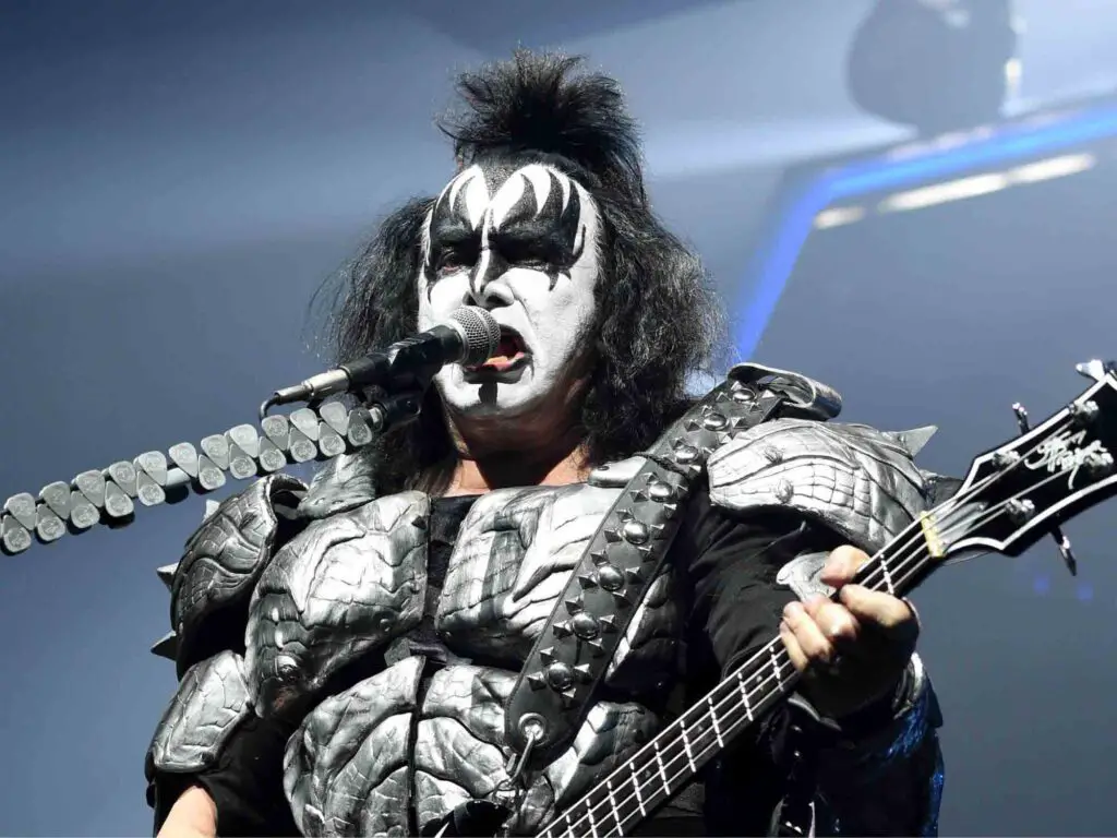Gene Simmons with makeup, costume, and guitar in a concert.