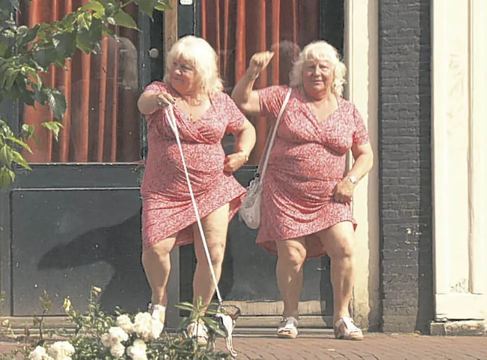 Martine and Louise Fokkens in a new documentary standing in front of a door wearing a pink dress, and claiming to each have 177,500 sexual partners.