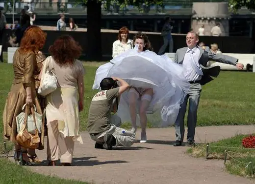 The wedding dress of the bride is blown away while the camera man takes a close up picture.