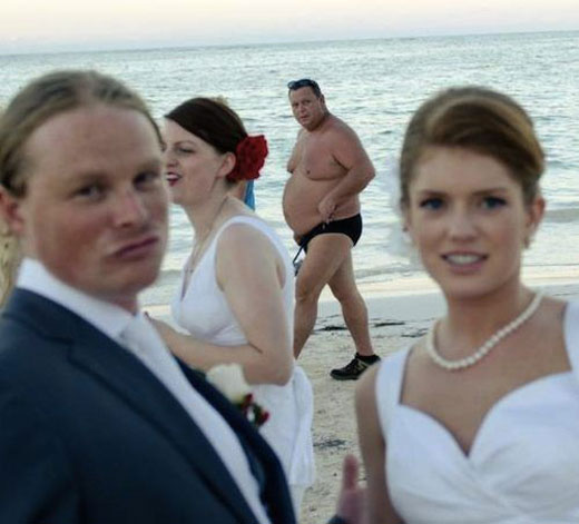 A guy wearing Speedo passes by during the bride and groom's a photo ops.