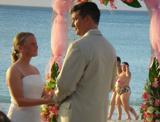 A nude beach goer passes on the background during a wedding.