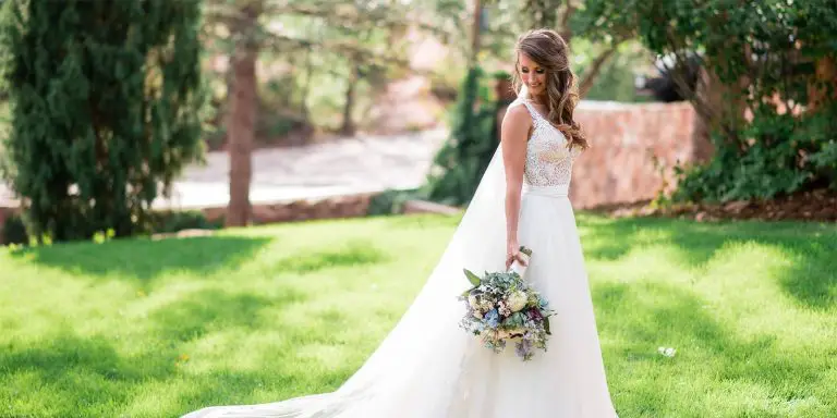 A woman holding a bouquet of flowers while wearing a very beautiful white dress during her wedding.
