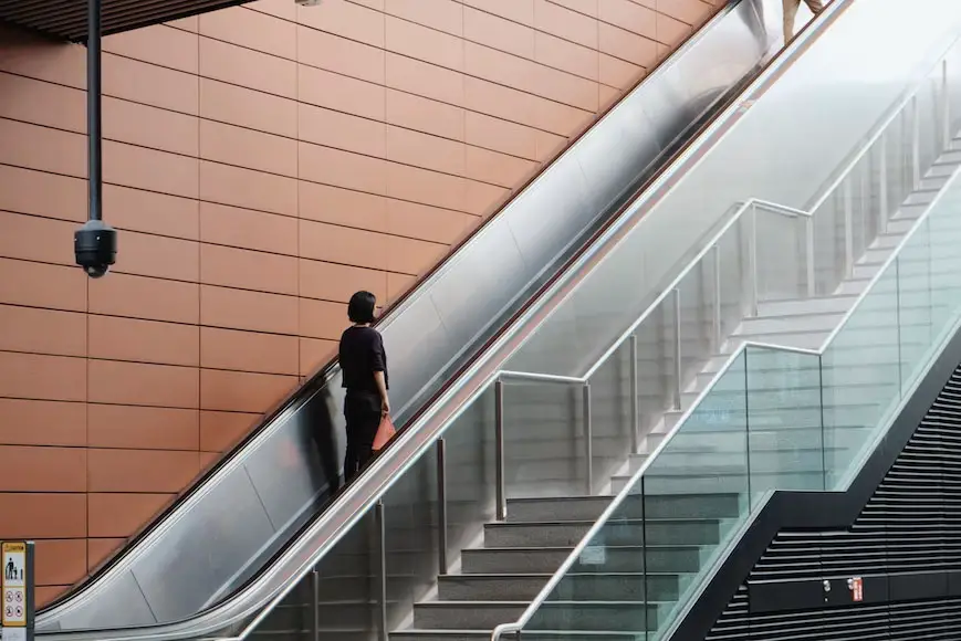 A woman riding on a moving staircase or an escalator.