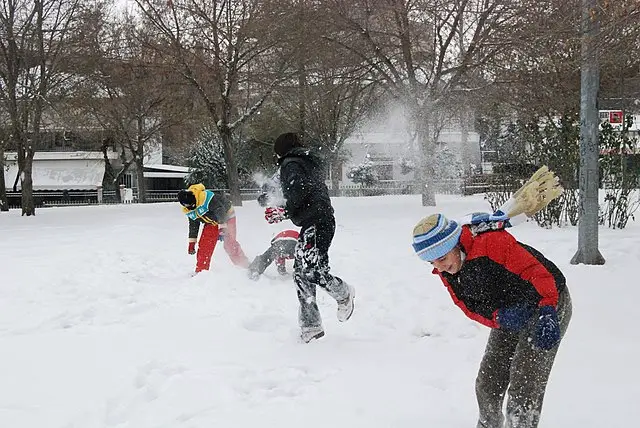 Kids in the snow playing snowball fight.