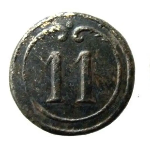 An old bronze button with the number 11 embossed in the middle.