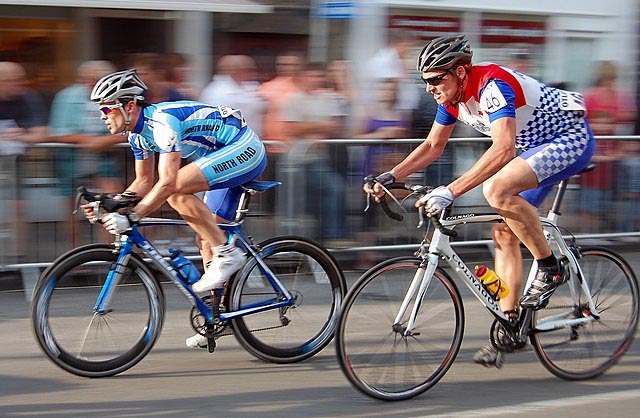 Two cyclists racing up to the finish line.