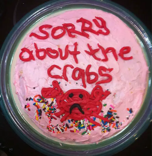A pink sorry cake that says, "Sorry about the crabs"