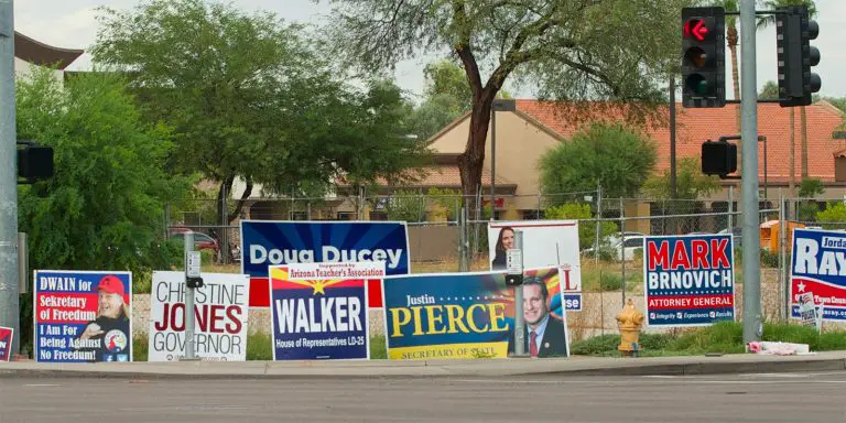 Campaign posters of candidates with some of them funny posted along the side of the street.