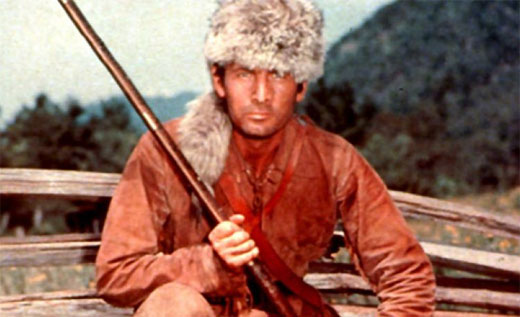 A person holding a rifle while wearing a coonskin cap.