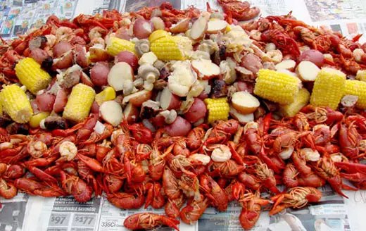 Cooked crawdads placed on the table with corn and other delicious foods.