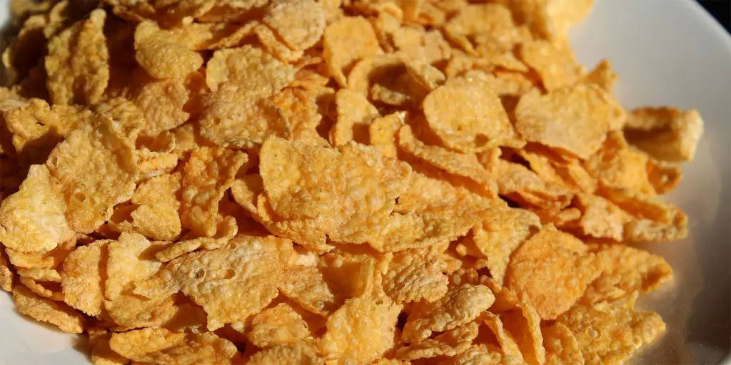 Yellow corn flakes on a white plate.